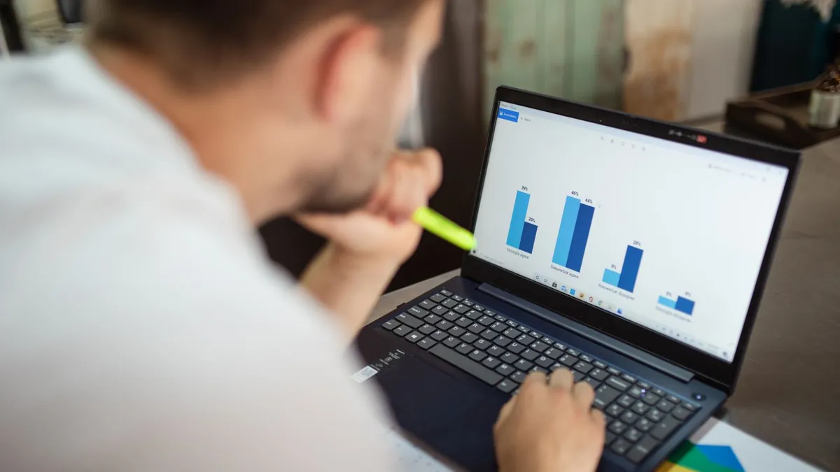 Laptop z wykresami kampanii wideo symbolizuje wspólne zarządzanie zasięgiem i częstotliwością reklam
