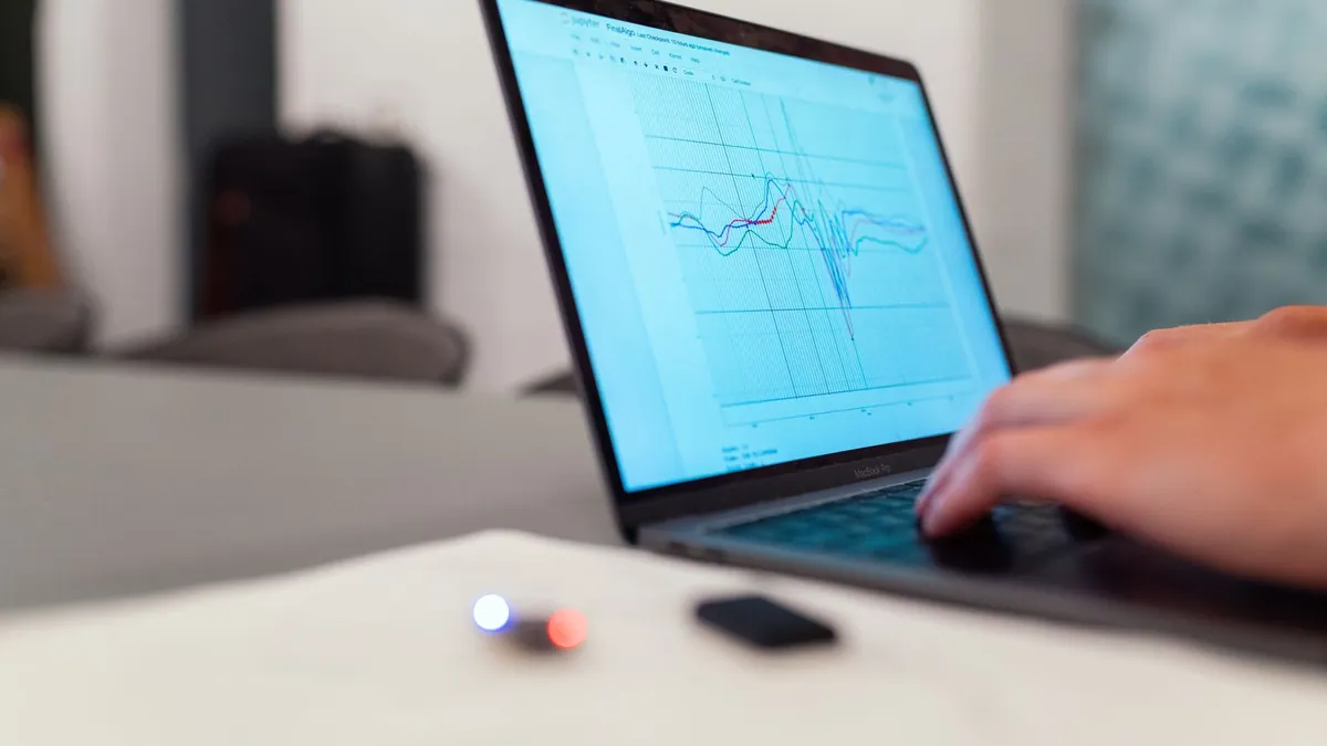 Analityk pracuje przy laptopie z raportami, symbolizując kontrolę nad zapytaniami, marką i stroną docelową kampanii