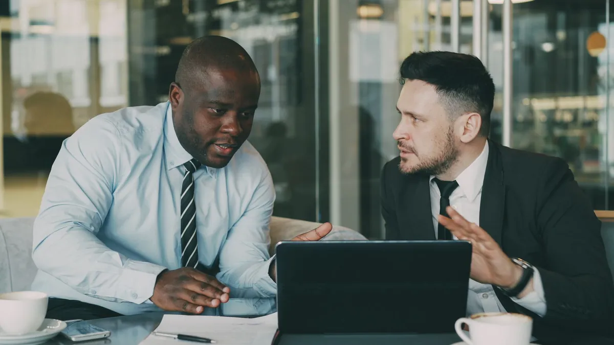 Dwóch specjalistów pracuje wspólnie przy laptopie, co symbolizuje szybsze tworzenie wariantów reklam i porządkowanie kreacji B2B w LinkedIn Ads