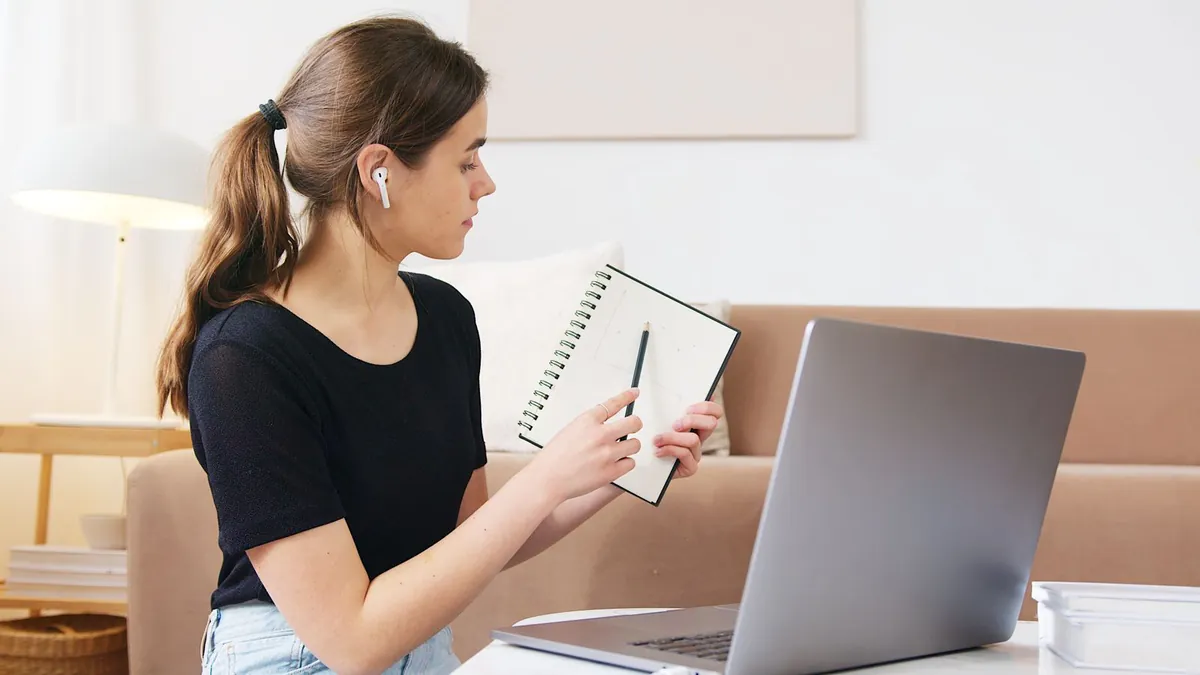 Kobieta uczestniczy w webinarze przy laptopie i notatniku, co symbolizuje kampanię wydarzenia B2B nastawioną na pipeline, a nie tylko liczbę rejestracji