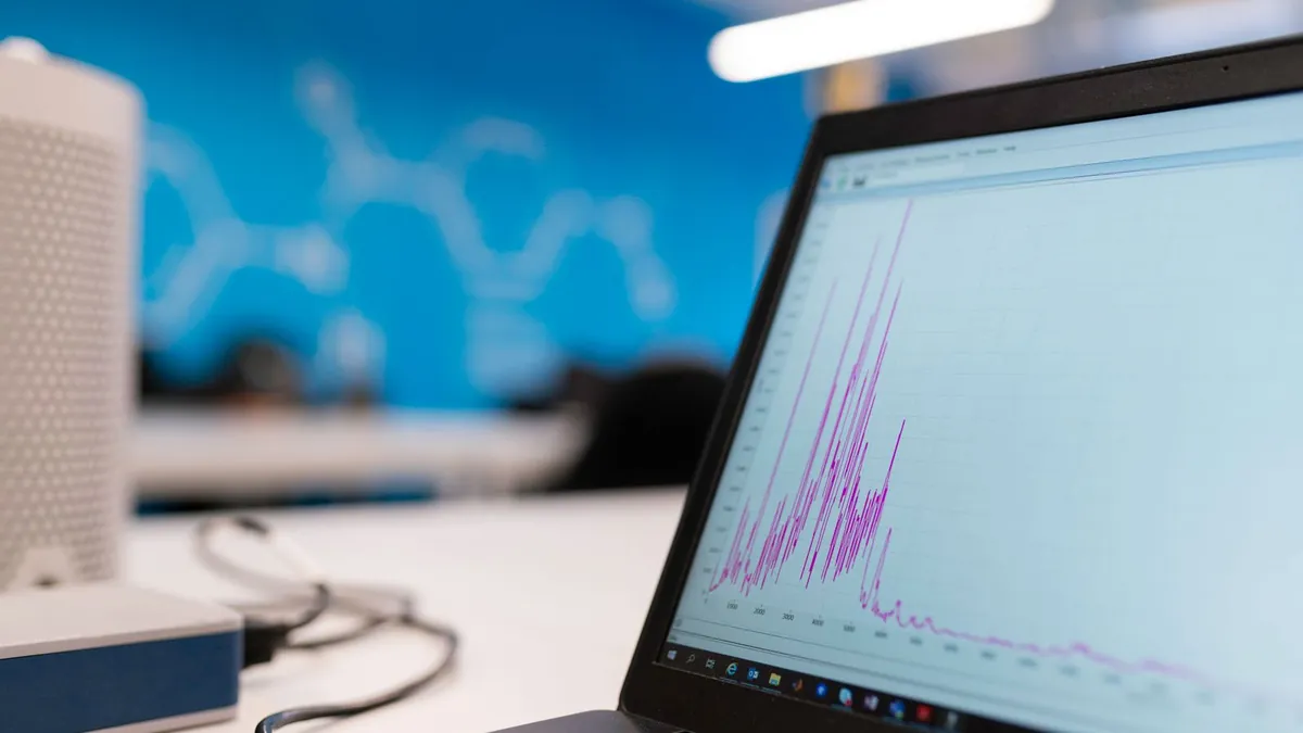 Laptop z wykresem analitycznym symbolizuje połączenie danych o zapytaniach, zachowaniu na stronie i diagnozie kampanii po kliknięciu