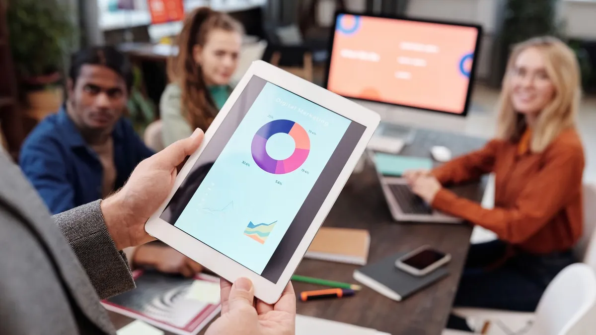 Osoba trzyma tablet z wykresem marketingowym, co symbolizuje lepszy pomiar kampanii shopping ads dzięki Tagowi, CAPI i porządkowi w grupach produktów