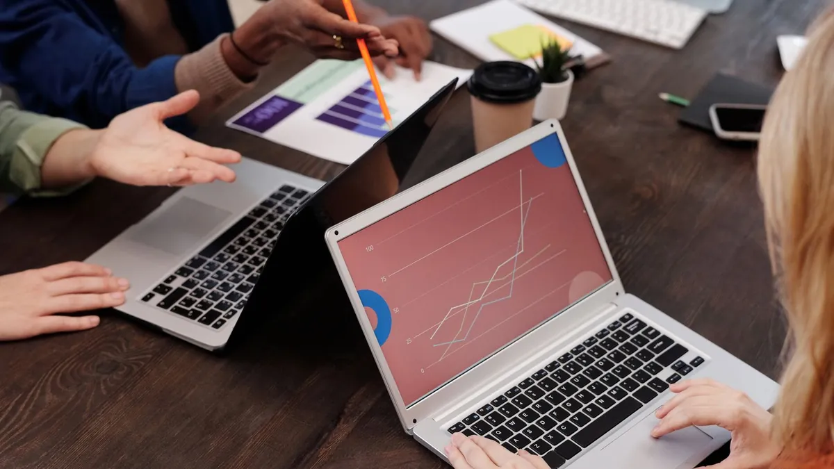 Zespół analizuje dane na laptopach, co symbolizuje dokładniejsze liczenie zasięgu i częstotliwości reklam na współdzielonych ekranach