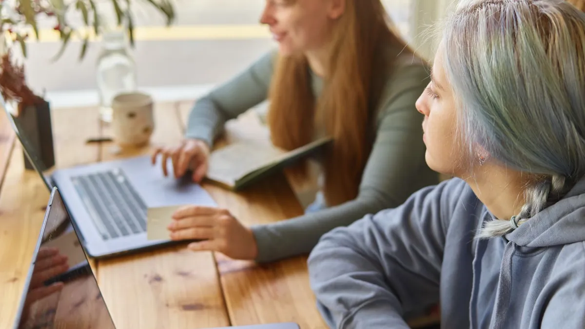 Dwie osoby pracują przy laptopie nad sprzedażą online, co symbolizuje integrację Shopify z reklamami Reddit i szybszy start kampanii produktowej