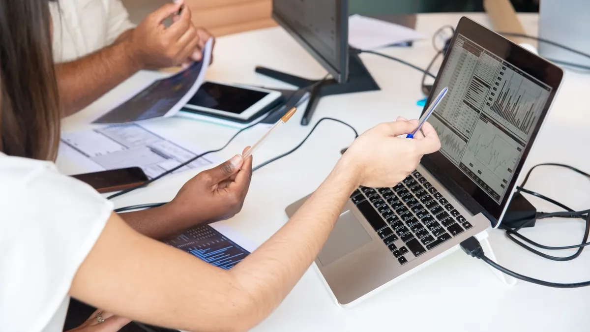 Dłonie wskazują wykresy na laptopie podczas omawiania doboru twórców i bezpieczeństwa kampanii