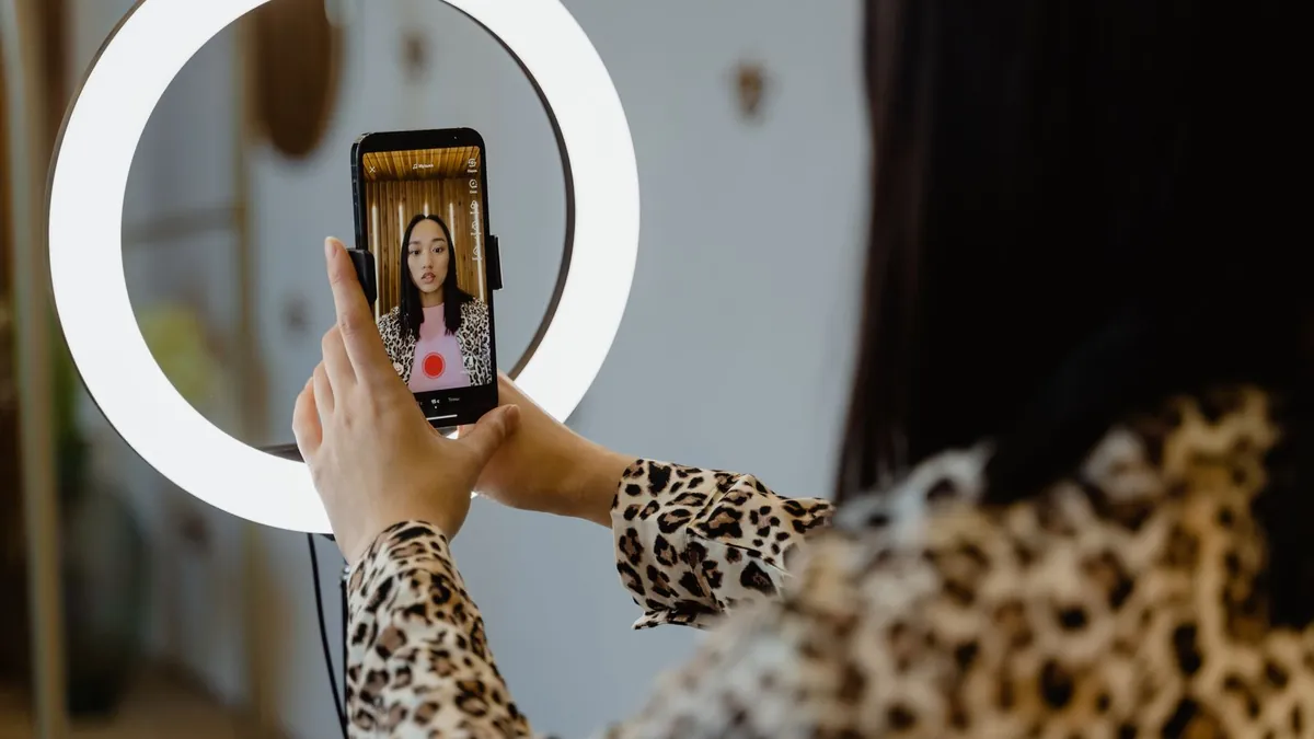Twórczyni nagrywa smartfonem przy ring light, co symbolizuje szybsze tworzenie reklam wideo dzięki narzędziom AI TikToka