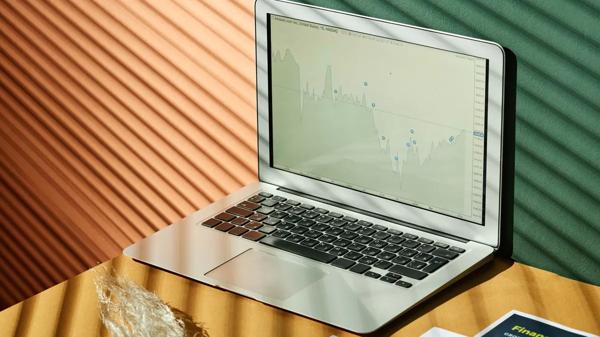 Laptop z wykresami oraz wydruki danych na oświetlonym stole